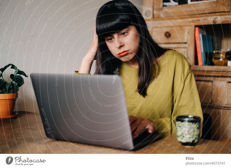 Woman sits bored at home in front of the laptop Notebook stressed deadline frustrated overwhelmed Exasperated home office labour online study Student Digital