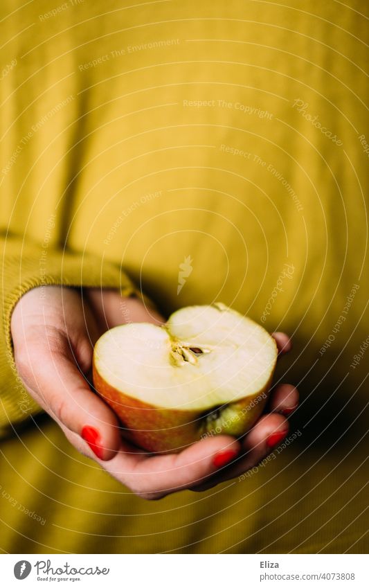 A woman holds an apple half in her hand Apple Half fruit salubriously Snow White Snack Yellow Hand Woman stop Delicious Nutrition Healthy Eating