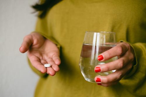 A woman holds a tablet and a glass of water in her hands. Taking medicine. Pill Medication headache tablet Ibuprofen Water Tumbler Healthy Illness Painkiller