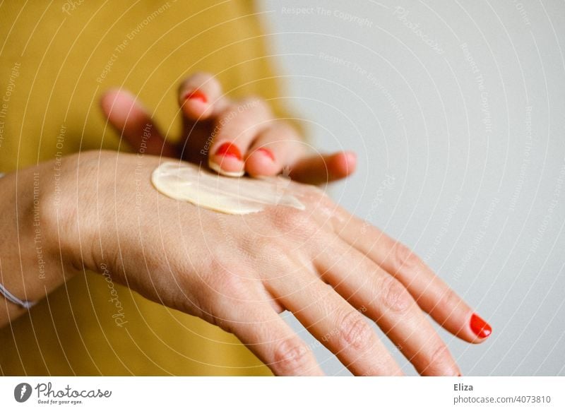 A woman creams her hands with a hand cream Put on cream Hand cream Personal hygiene dry skin Skin care Cosmetics Cream Woman Nail polish hand care