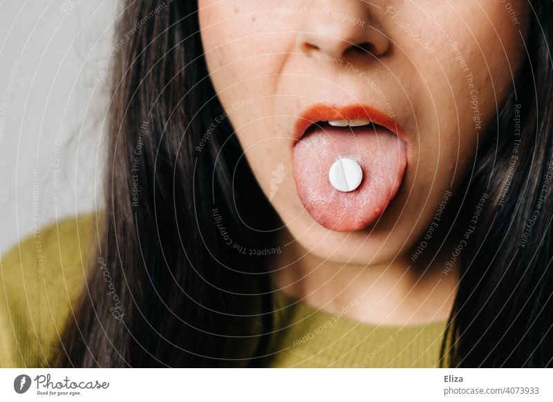 Woman with tablet on her tongue. Medication intake. Pill Tongue Earn medication intake medicine Painkiller Mouth Medical treatment Close-up White Addiction