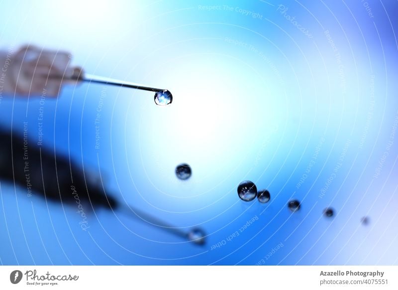 Close up image of a syringe with droplet on the needle addiction ampoule antidote blue bokeh closeup concept coronavirus dark death dependency dramatic droplets