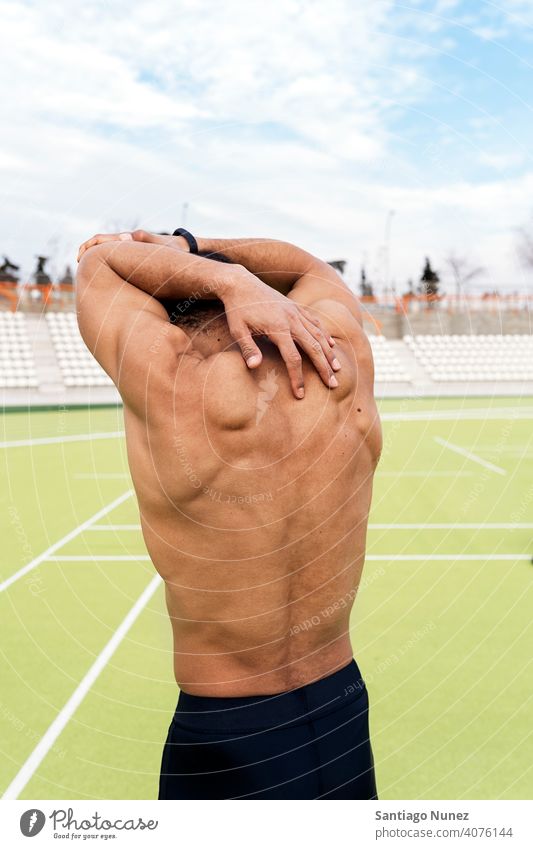 Black Athlete Stretching in Sports Track back view african american stretching arms shirtless sports track athlete faceless anonymous unrecognized portrait