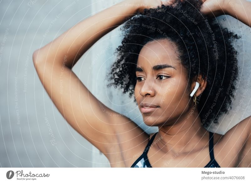 Afro athletic woman standing outdoors. fitness athlete sport exercise resting break ear pods enjoying relaxation leisure city sporty earbuds sportswoman active