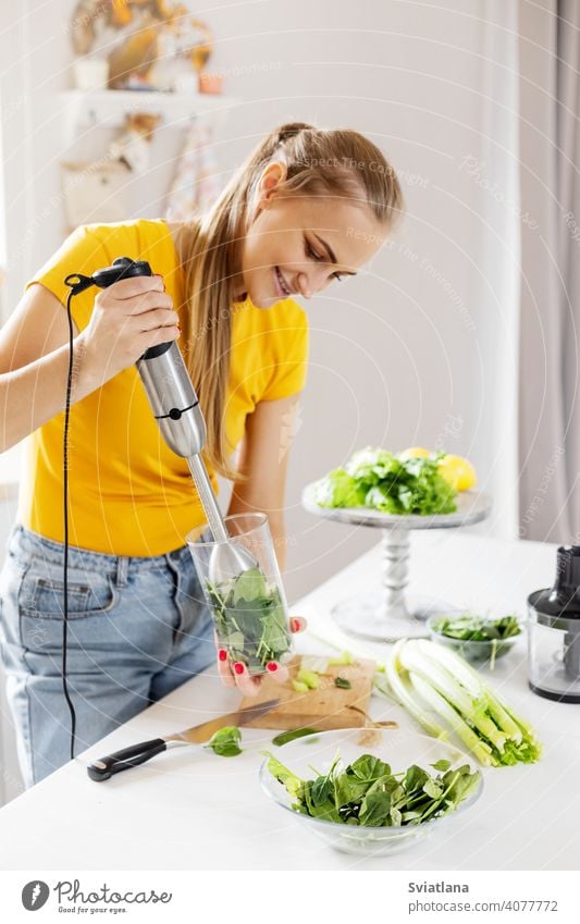 A young woman makes a smoothie from vegetables and fruits. The concept of a healthy lifestyle and slimness. blender green food detox making dieting vegetarian