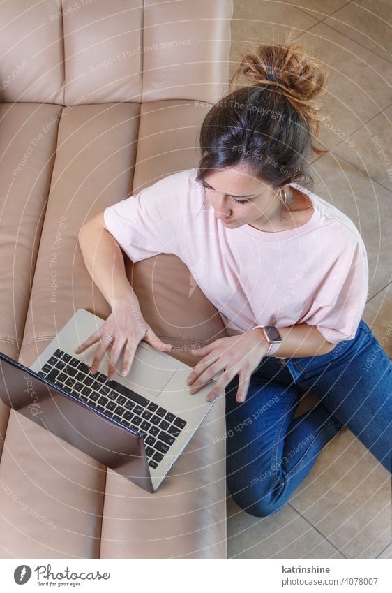 Young women working with laptop while sitting on the floor at home wear mockup t-shirt learn student Lifestyle top view jeans coffee to go cup serious