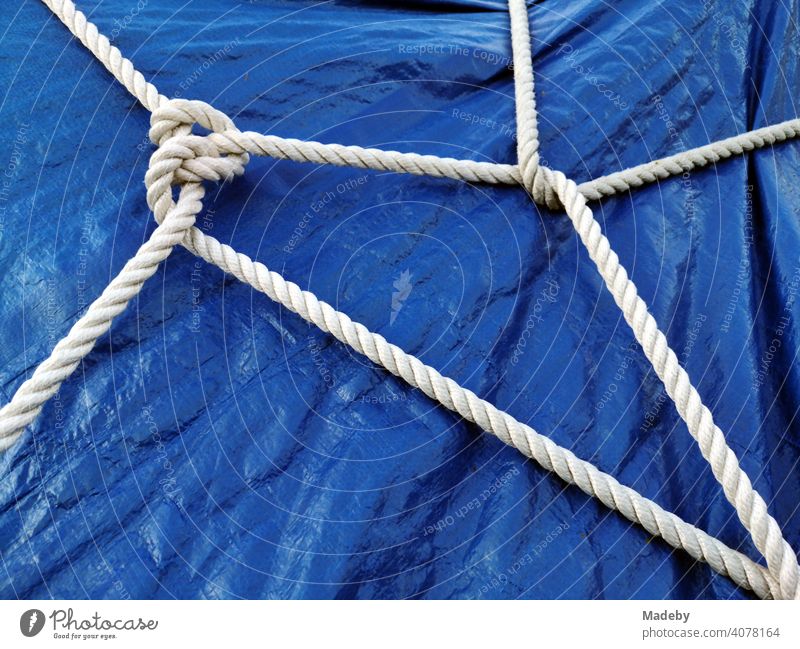 White ship's rope as still life on a blue tarpaulin made of plastic over a boat on a trailer in Oerlinghausen at the Hermannsweg near Bielefeld in the Teutoburg Forest in East Westphalia-Lippe