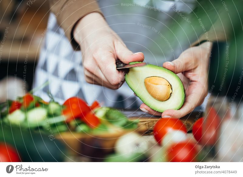 Woman peeling an avocado. salad tomato hand midsection female selective focus close up knife making wooden vegan food healthy white lifestyle indoors table