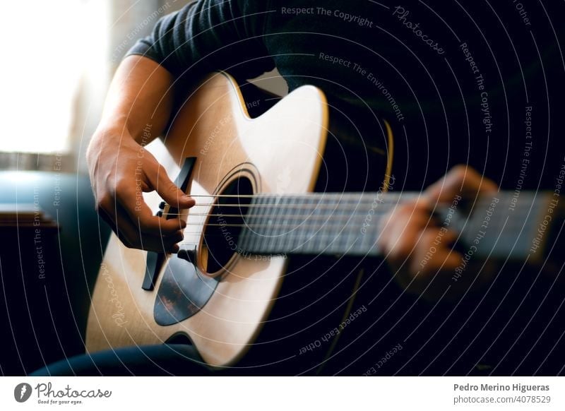 Young man playing acoustic guitar music musician room instrument male musical song young adult person people home guitarist lifestyle sound hobby leisure casual