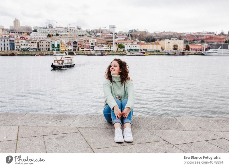 young beautiful woman sitting by the river at sunset enjoying Porto views. Travel concept travel city sightseeing urban caucasian people tour tourism spring