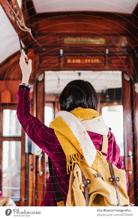 young caucasian backpacker woman sightseeing Porto views standing on a train. Travel concept travel city urban public transport yellow sun river spring