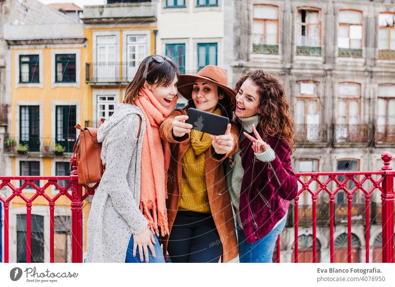 three women sightseeing Porto views and taking picture with mobile phone. Travel and friendship concept travel backpacker city urban river sunset tourist