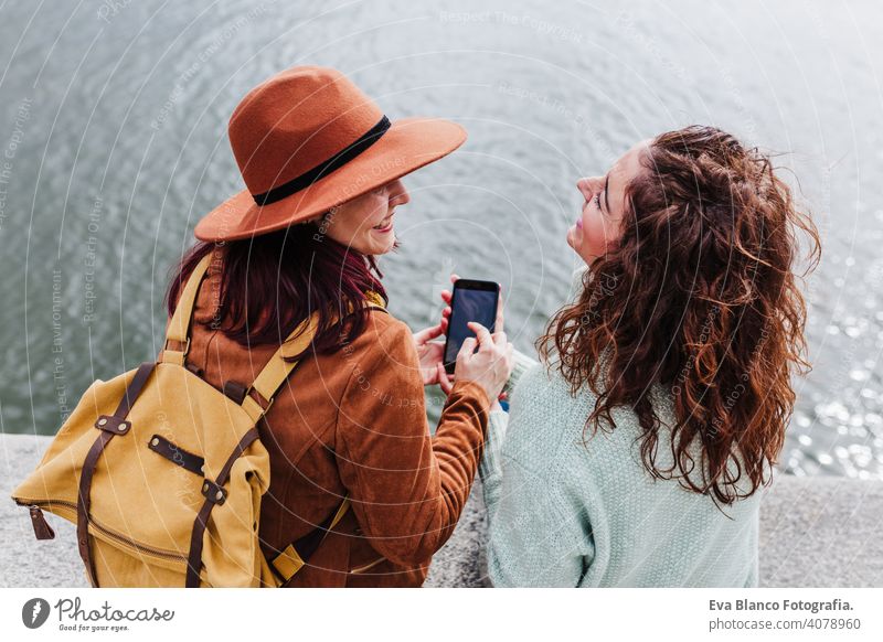 two women sightseeing Porto views by the river and taking picture with mobile phone. Travel and friendship concept city technology travel backpacker urban