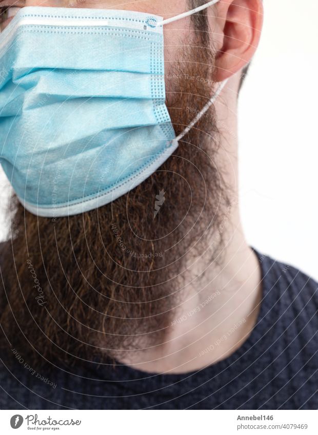 Caucasian young bearded adult man wearing a protective or surgical mask to avoid pollution and contagious virus and diseases isolated on white background, Covid-19, coronavirus,health,beard, epidemic concept