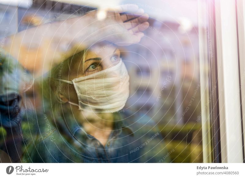 Senior woman wearing protective face mask looking out of window at home people senior mature casual female Caucasian elderly house old aging domestic life