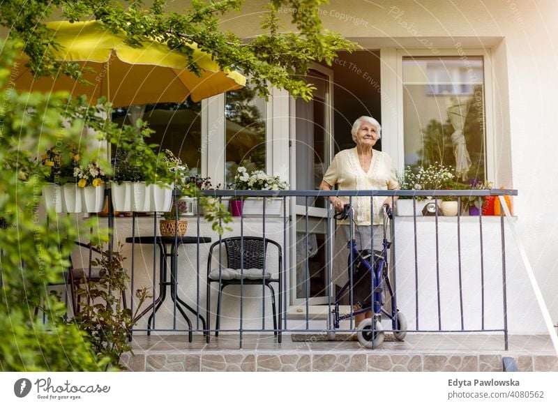 Senior woman with mobility walker standing on her balcony people senior mature casual female Caucasian elderly home house old aging domestic life grandmother