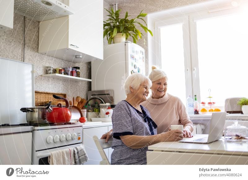 Adult daughter teaching her elderly mother to use laptop computer two people bonding family love together visit parent friends friendly assistance help helping