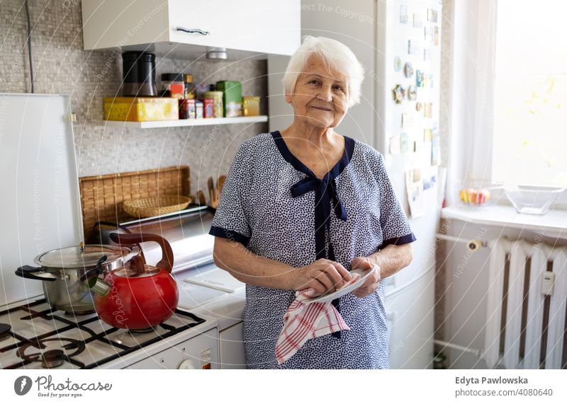 Senior woman in her kitchen drying dishes people senior mature casual female Caucasian elderly home house old aging domestic life grandmother pensioner
