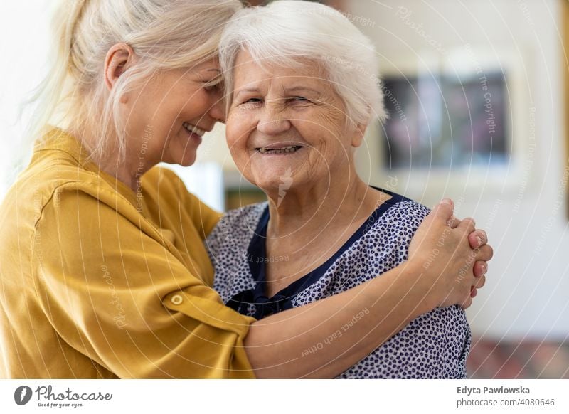 Woman hugging her elderly mother smiling happy enjoying positivity vitality confidence people woman senior mature casual female Caucasian home house old aging