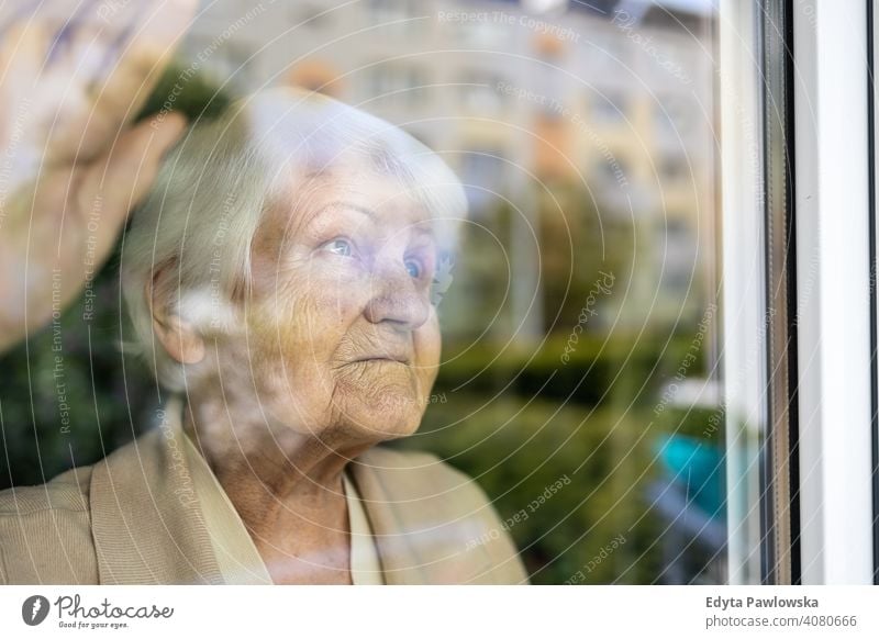 Senior woman looking out of window at home sad lonely unhappy depression uncertainty anxiety worried grief sadness loss problem crisis serious nostalgia