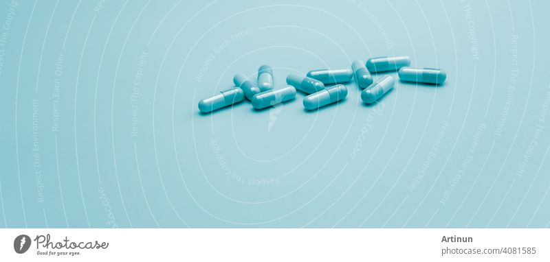 Blue antibiotic capsule pills on pastel blue background. Pharmacy web banner. Antibiotic drug resistance. Antimicrobial capsule pills with space. Health budget and policy. Pharmaceutical industry.