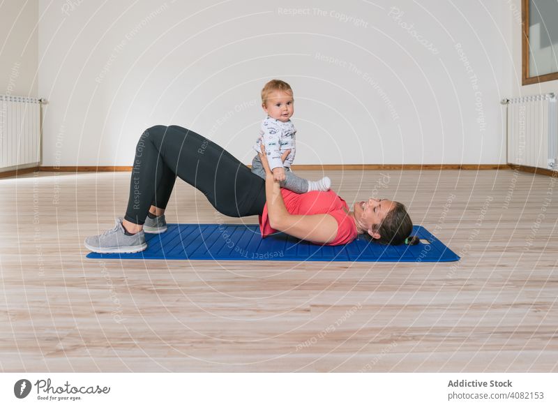 Mother exercising with baby in gym mother exercise workout lying floor abs fitness modern lifestyle woman kids children infants happy smiling cheerful joy