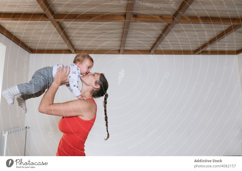 Woman kissing baby in gym mother lifting workout fitness modern lifestyle woman kid child infant training sportswear leisure healthy wellness well being tender