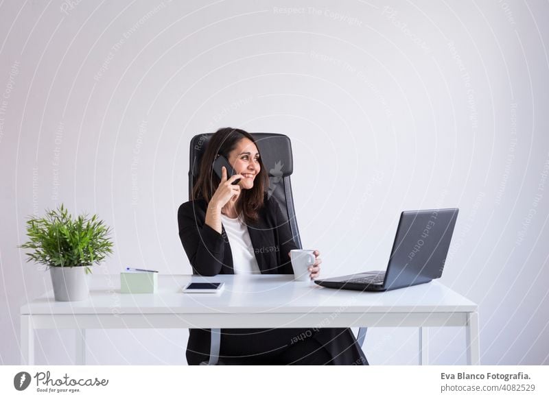 beautiful young Business woman using his laptop in the office and talking on her mobile phone. Business Concept.white backgrounds. Indoors computer worker