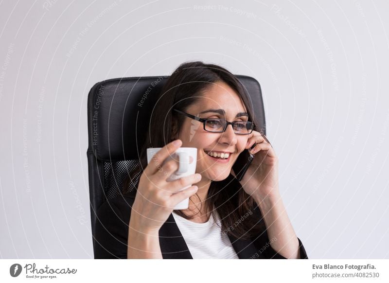 beautiful young Business woman talking on her mobile phone in the office and holding a cup of coffee. Business Concept. Lifestyle. Indoors computer laptop