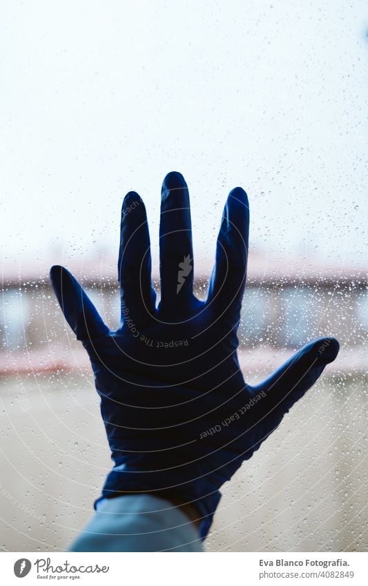 hand of a doctor on a window, rainy day. Coronavirus covid-19 concept professional corona virus hospital working infection glove wearing safety epidemic