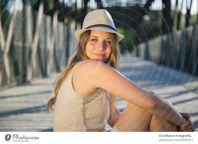 portrait of a young woman at sunset Portrait outdoors happy blonde hat blue eyes bridge summer sunny hair happiness lifestyle face beautiful fun white person