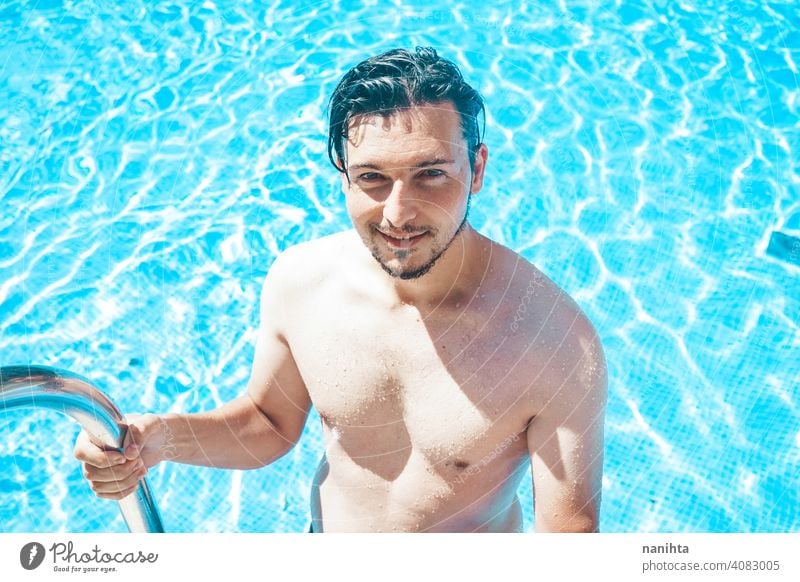 Young handsome man posing near a pool attractive sexy male swimming pool summer skin beard guy smile tan blue water party portrait portraiture real people cool