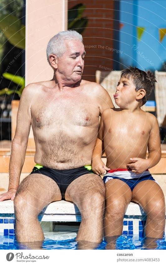 Grandpa and grandson smiling on a swimming pool side 60s adult boy caucasian cheerful child childhood children complicity elderly enjoying family father