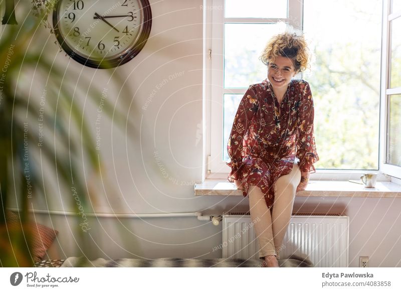 Relaxed woman at home sitting at the window happy smiling cheerful apartment leisure bedroom house alone people caucasian adult indoors person casual attractive