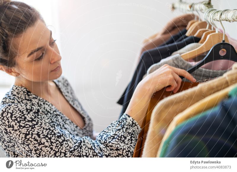 Young woman shopping at a clothing boutique fashion clothes fashionable rack choosing retail store sale hanger customer style shopper shopaholic wardrobe choice