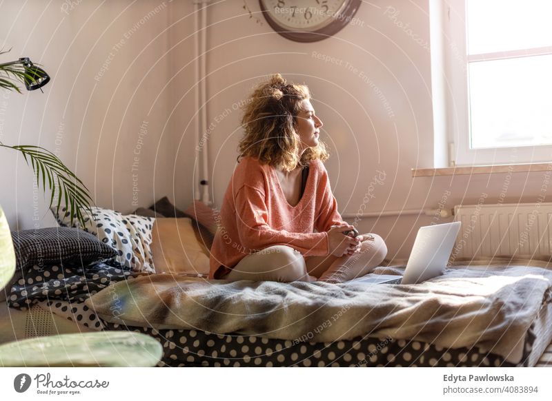 Young woman working in bed at home with laptop education learning studying homework book e-learning technology computer internet online communication wireless