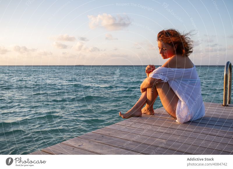 Young woman on pier near sea sitting smiling sky clouds evening maldives sensual young female resort vacation paradise ocean freedom carefree lifestyle leisure