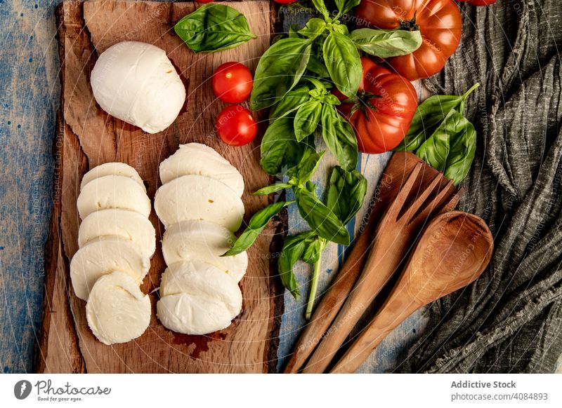 Salad ingredients on board and napkin tomatoes cheese basil salad mozzarella leaves fresh ripe food meal kitchen italian cuisine healthy lunch gourmet snack