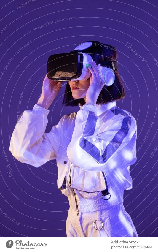 Woman in VR headset woman vr virtual reality technology neon light touching device digital innovation young person glasses asian modern entertainment game