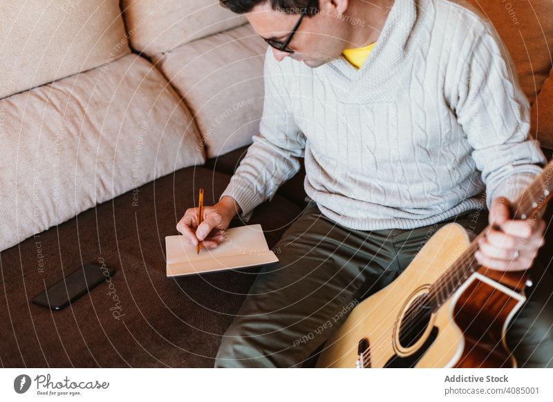 Musician writing in a notebook guitar musician acoustic student apartment pencil home man hand space young play entertainment guy instrument musical guitarist