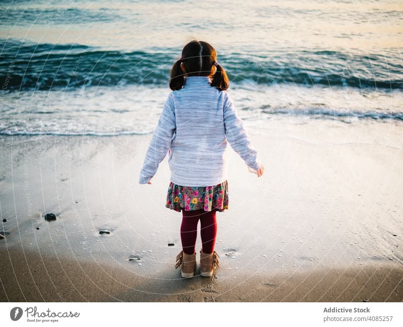 back view of little girl looking at sea beach freedom adorable summer ocean standing kids sand water travel white beautiful child vacation blue caucasian