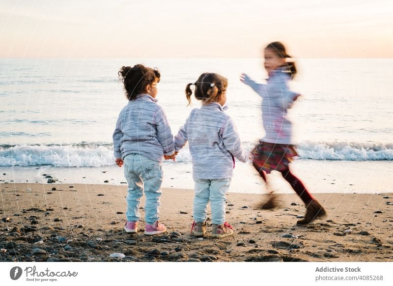 kids playing at the beach running fun children holding hands sea sister joy girl friends childhood three young sand winter boy happy lifestyle vacation water