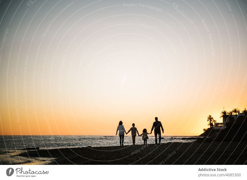 Silhouette of family holding hands at sunset together silhouette beach vacation walking parents son sea summer sand travel holiday tropical leisure shore relax