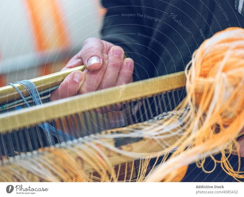 Crop weaver working with thread spinning frame wooden craft handmade old floor tiled textile wool cotton aged shabby weathered process occupation job