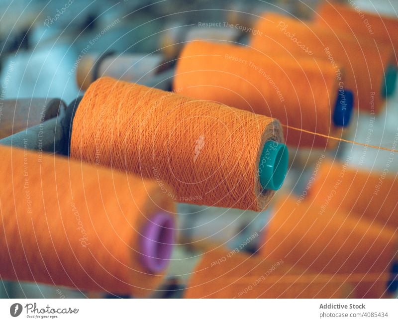 Spools of thread on weaver loom spools industry factory fiber cotton textile fabric machine manufacturing string craft yarn cloth orange bright color material