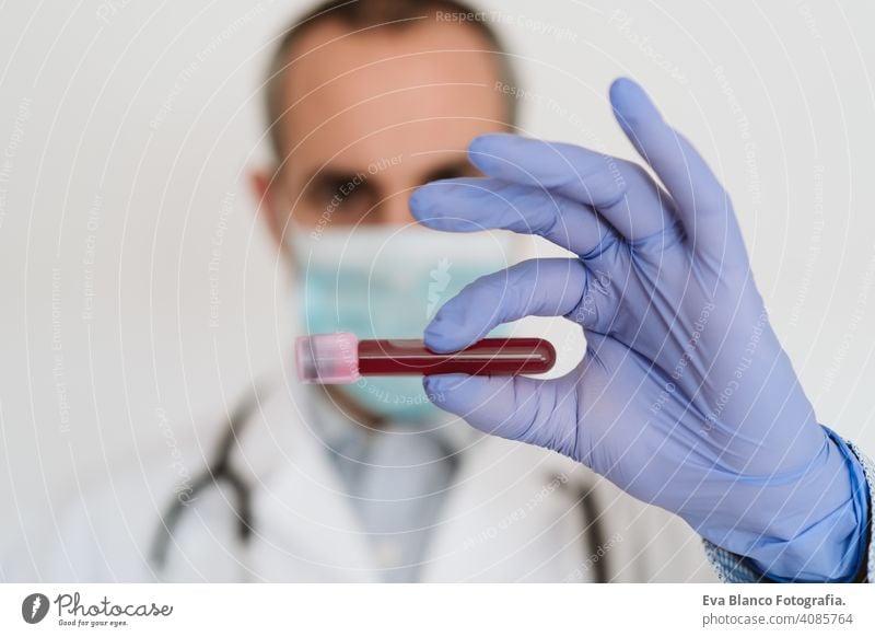 caucasian doctor holding test tube with blood for 2019-nCoV analyzing. Chinese Corona virus blood test concept analysis vaccine research bacterial portrait man
