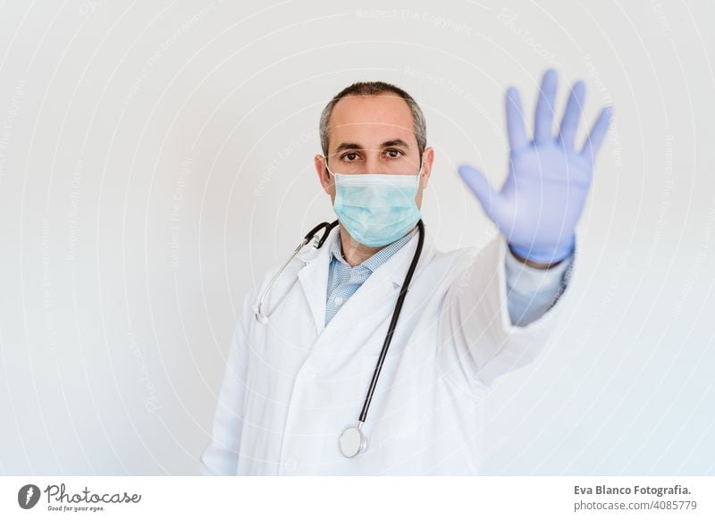 portrait of doctor wearing protective mask and gloves indoors. Making a stop sign with hand. Corona virus concept man professional corona virus hospital working