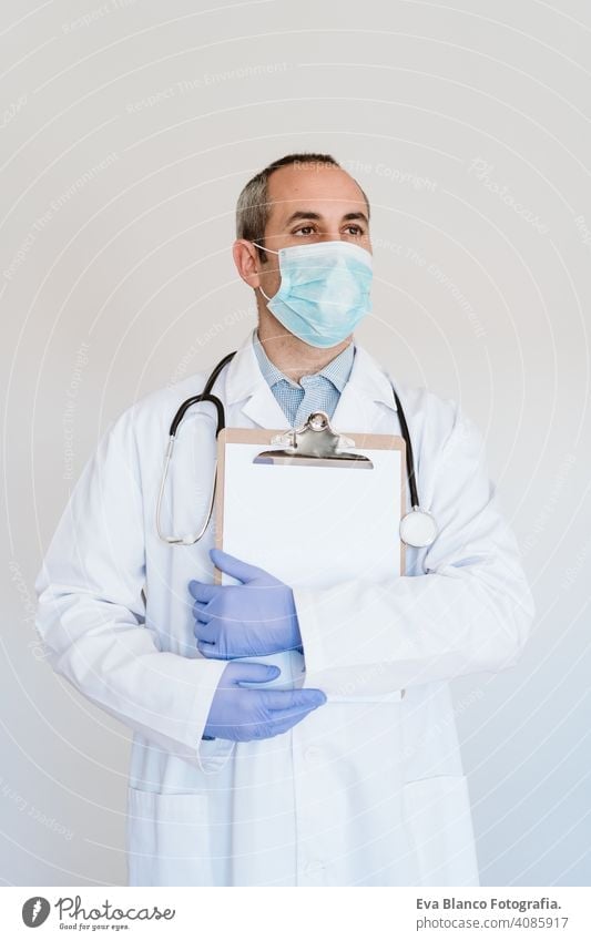 portrait of caucasian doctor using protective gloves and mask. Working on a folder. Chinese Corona virus concept. 2019-nCoV man professional corona virus