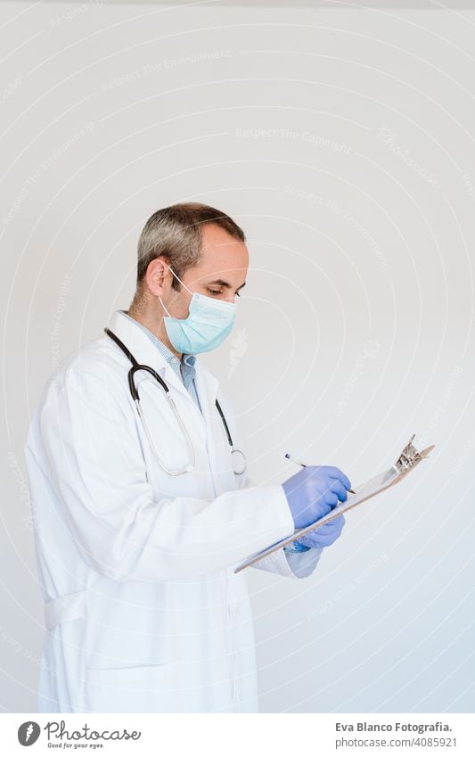 portrait of caucasian doctor using protective gloves and mask. Working on a folder. Chinese Corona virus concept. 2019-nCoV man professional corona virus