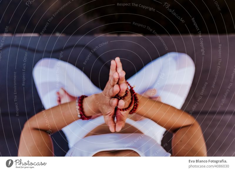 close up view of unrecognizable young asian woman doing yoga in a park. Sitting on the bridge with praying hands position and using Mala necklace. Yoga and healthy lifestyle concept. Top view